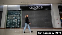 Женщина проходит мимо закрытого магазина Adidas в торговом центре в городе Чехов под Москвой, 27 мая 2022 года. Фото AFP