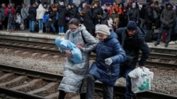 Люди переходят железнодорожные пути на вокзале в Киеве, откуда отходит эвакуционный поезд во Львов. Фото: Reuters