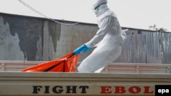 Либерия: работник столичной больницы переносит в крематорий тело умершего от Эболы. Монровия, 13 октября 2014 г.