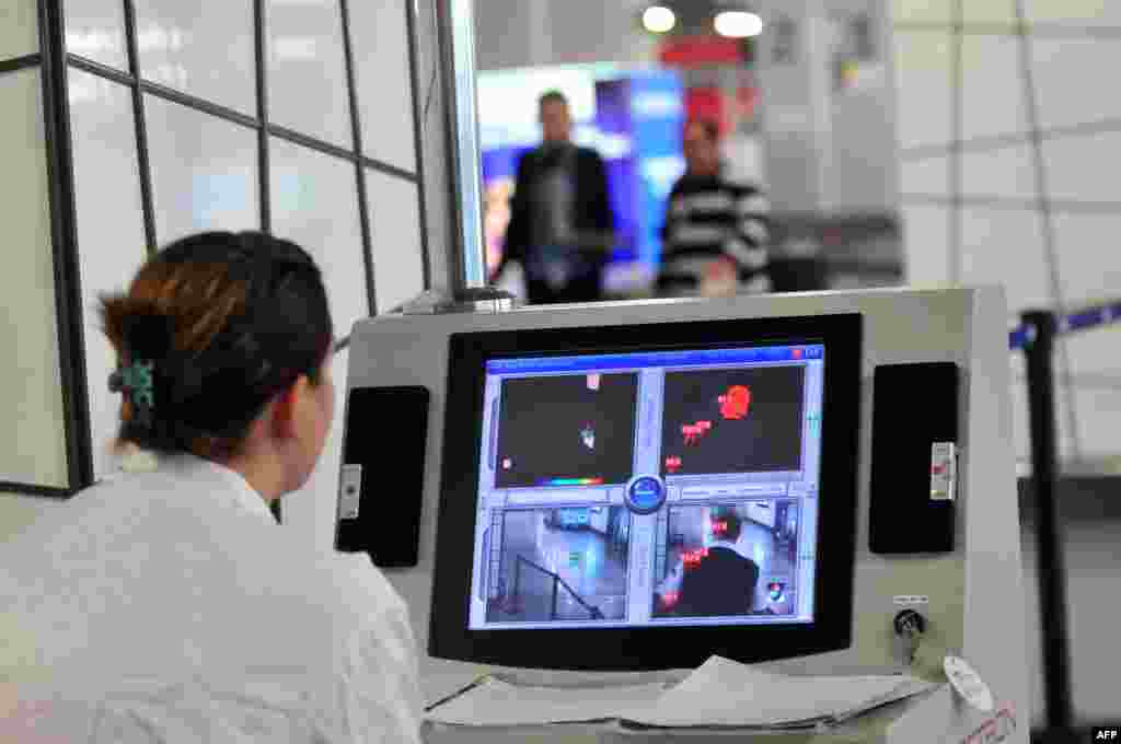 Медицинский работник проверяет тепловизионной камерой туристов после их прибытия в отель Alexander the Great недалеко от столицы Македонии - Скопье. Македония. 10 октября 2014