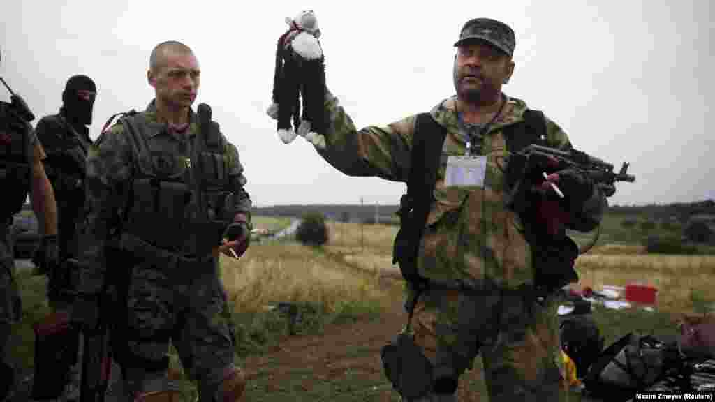 Один из пророссийских сепаратистов держит в руках игрушку, принадлежащую ребенку, пассажиру "Боинга" Малайзийских авиалиний рейса МН17. Самолет, который летел из Нидерландов в Малайзию, был сбит 17 июля 2014 года в небе над Донбассом, обломки упали недалеко от деревни Грабово на территории так называемой ДНР. Погибли 298 человек. Международная группа криминалистов (JIT) считает, что "Боинг" был сбит ракетой, выпущенной из российской установки "Бук" с территории сепаратистов. При этом установкой с высокой вероятностью управляли российские военные, и она была привезена из России в Украину незадолго до катастрофы. По данным JIT, "Бук" с бортовым номером 332 стоял на вооружении 53-й бригады ВС РФ (войсковая часть 32406), расквартированной под Курском