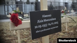 Памятный крест с именем одной из жертв обстрела в Мариуполе