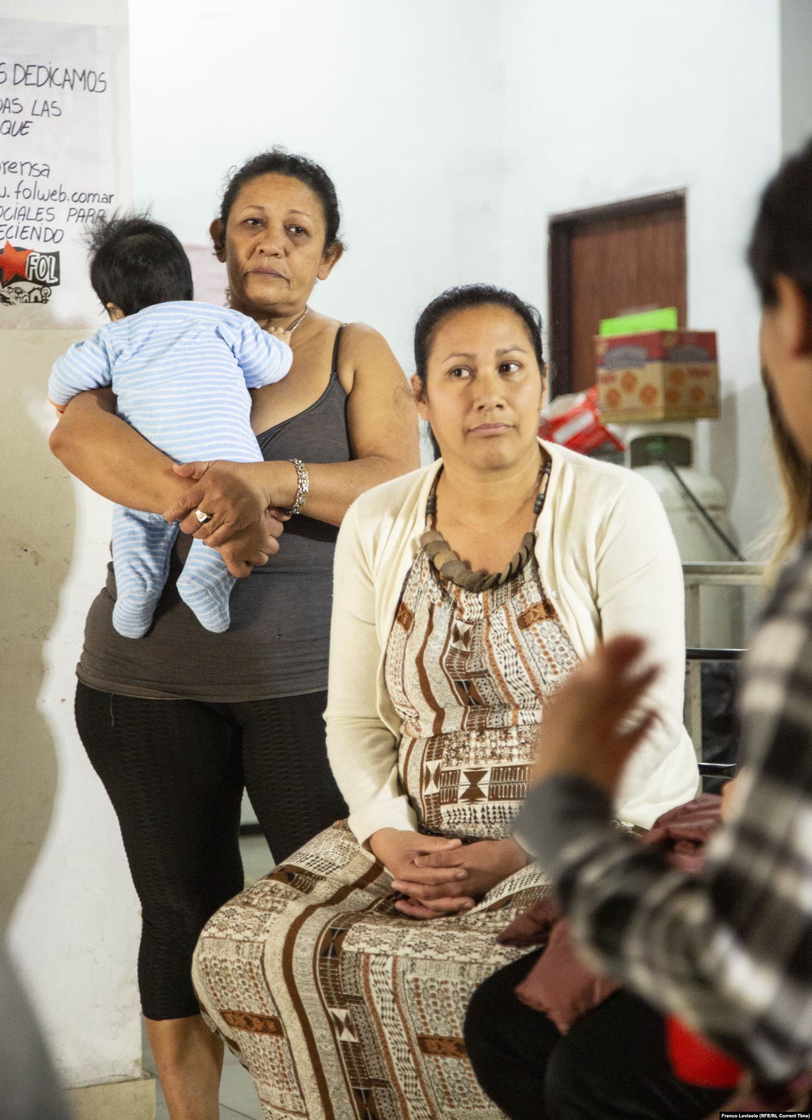 (справа налево) Мирта и Сельса с новорождённым сыном Мирты на руках. Обе женщины помогают готовить в бесплатной столовой из продуктов, которые привозит Карлос и его коллеги. Фото: Франко Ловисоло