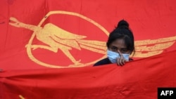 Девушка на фоне флага "Национальной лиги за демократию" во время протеста против военного переворота в Янгоне 7 февраля