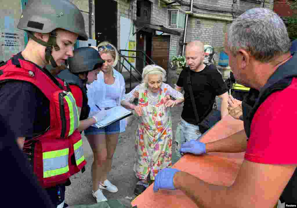 Медики  оказывают помощь пострадавшей во время российского обстрела жительнице многоэтажки в Харькове, фото Reuters