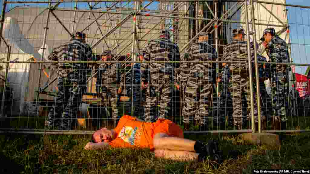 Обессиленный фанат на фоне ОМОНа на фестивале "Нашествие-2015"