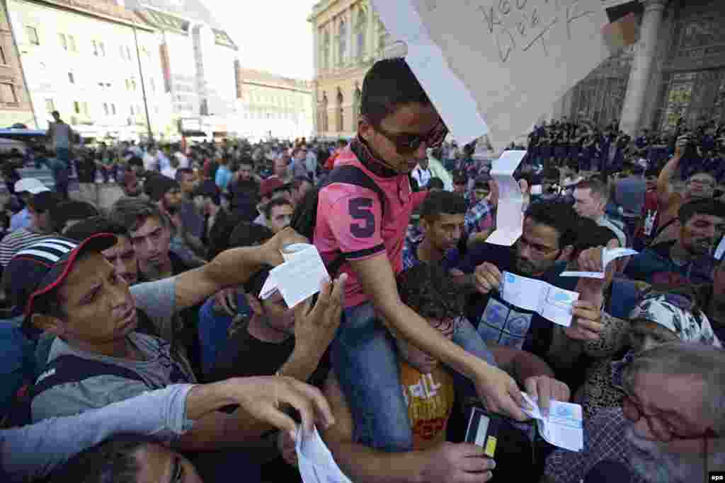 Мигранты получают билеты на поезда 