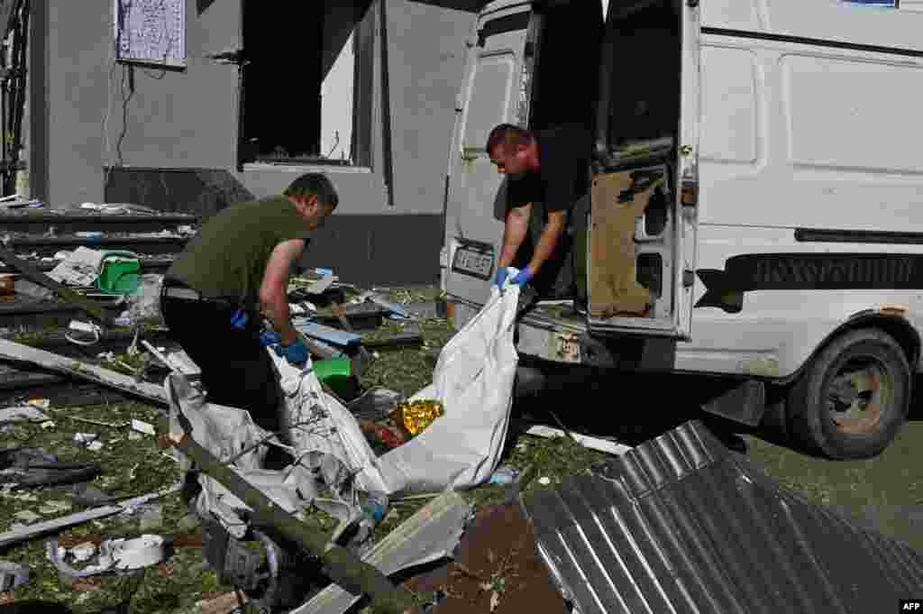 Работники коммунальных служб Харькова эвакуируют тело одного из людей, погибших в результате российского удара, 22 июня 2024 года, фото  AFP