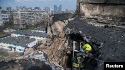 Пожарный работает в жилом доме, пострадавшем от удара российского беспилотника, Киев, Украина, март 2025 года